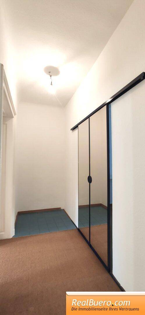 Flur mit braunem Teppichboden und einer großen Spiegelschiebetür, die den Raum optisch erweitert.