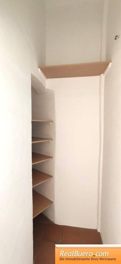 Kleiner Abstellraum mit Holzregalen, ideal für zusätzlichen Stauraum.