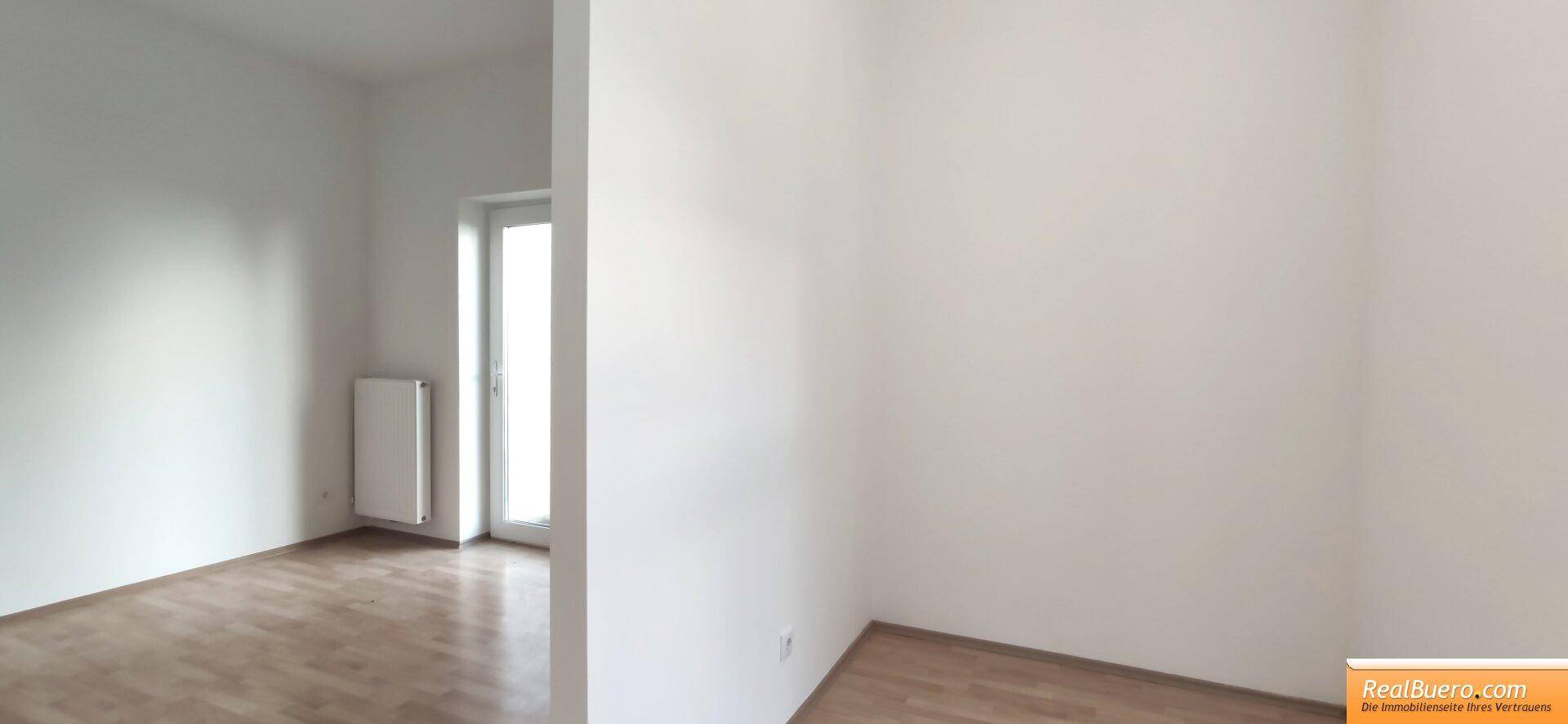 Weitläufiges, helles Zimmer mit Holzboden und Fenster, das viel Licht spendet und geräumig wirkt.