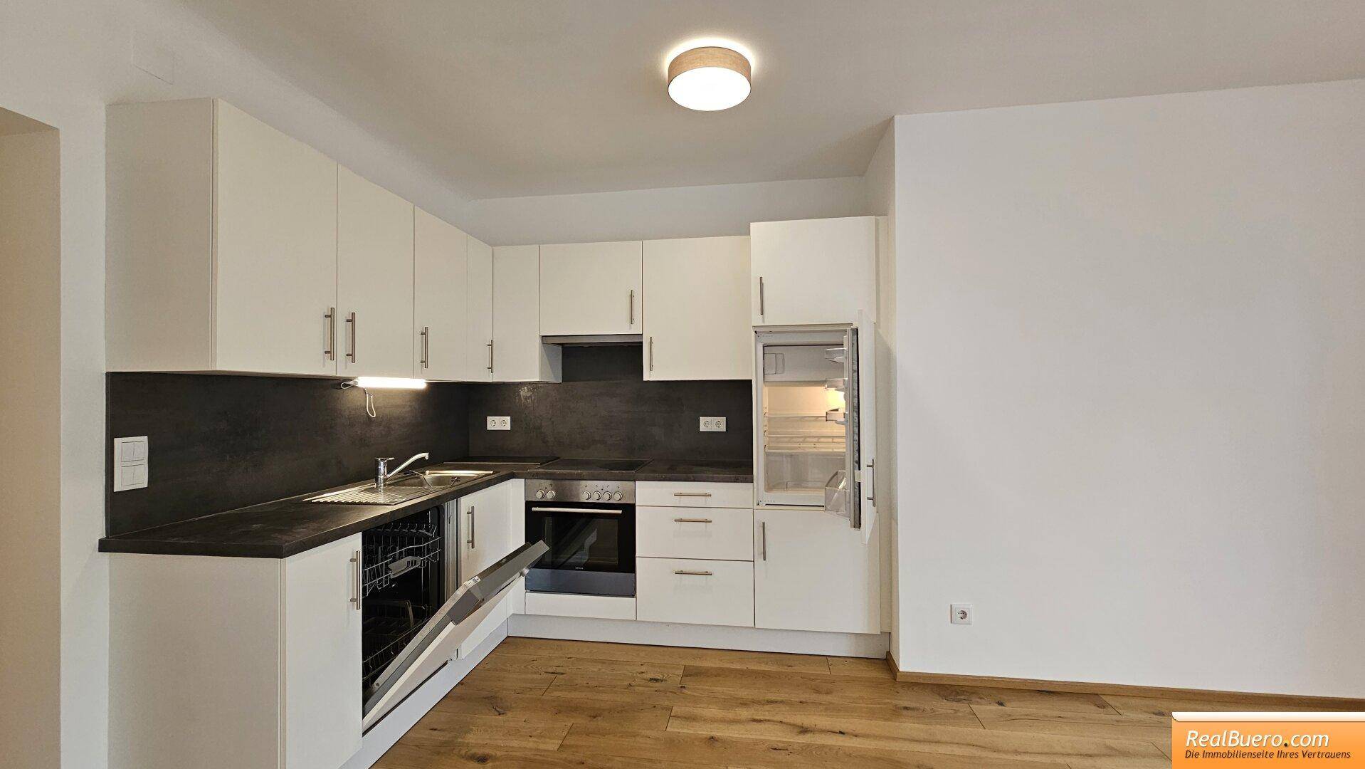 Funktionale Einbauküche mit geöffnetem Geschirrspüler und Kühlschrank in hellem Design.