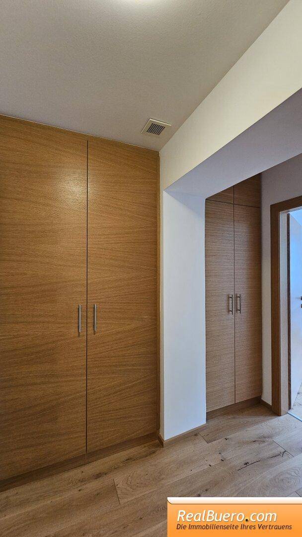 Flur mit eingebauten Holzschränken und passendem Holzboden für zusätzlichen Stauraum.