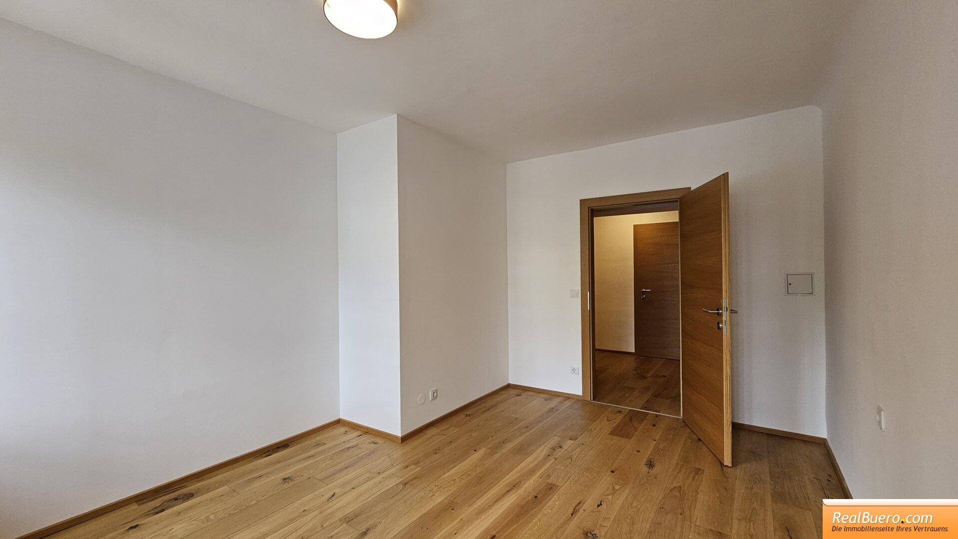 Leeres Schlafzimmer mit Holzboden und offener Holztür, bietet viel Gestaltungspotenzial.