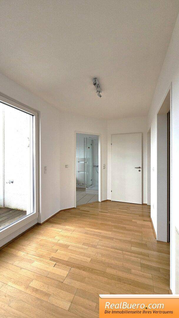 Heller Flur mit Parkettboden und Zugang zu weiteren Räumen und einem Balkon.
