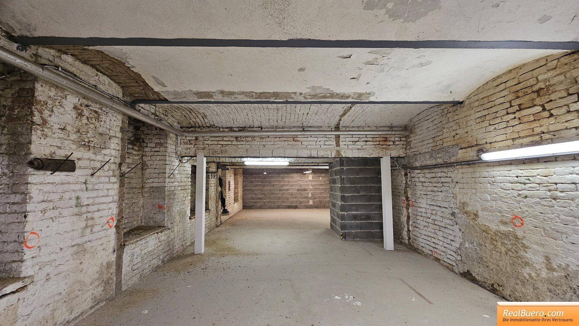 Geräumiger Kellerbereich mit freiliegenden Ziegeln, Betonboden und sichtbaren Installationen. Die gewölbte Decke verleiht dem Raum Charakter.