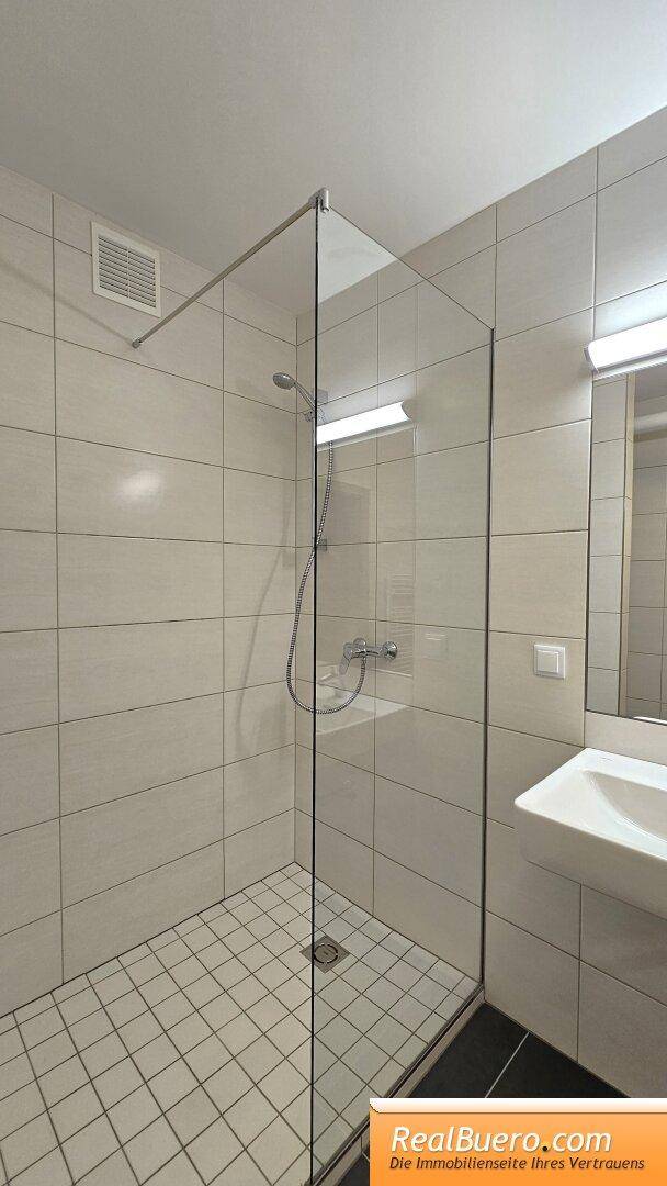 Bad mit Dusche, Toilette, Handwaschbecken, Handtuchtrockner und Waschmachinenanschluss