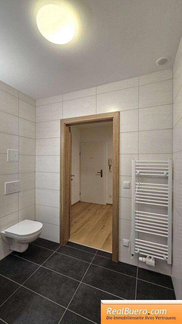 Bad mit Dusche, Toilette, Handwaschbecken, Handtuchtrockner und Waschmachinenanschluss
