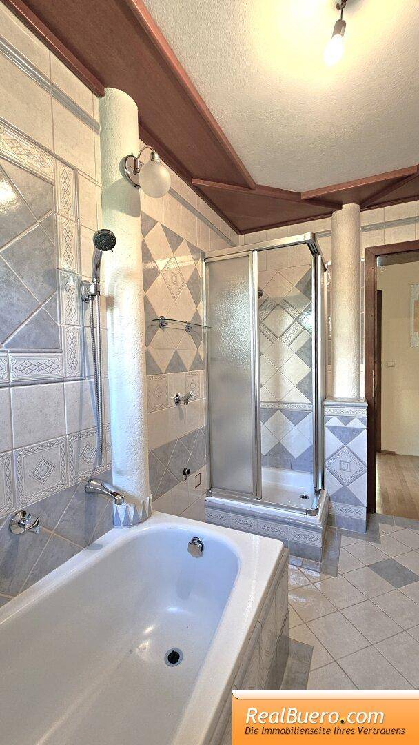 Badezimmer mit Wanne, Dusche, Handwaschbecken und Waschmachinenanschluss