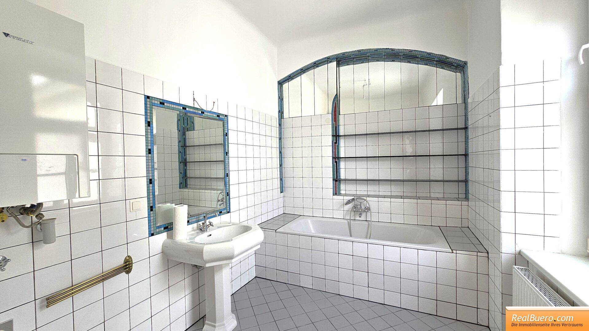 Badezimmer mit Wanne, Handwaschbecken, Waschmaschinenanschluss und Fenster