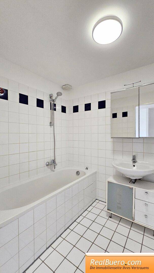 Badezimmer mit Wanne, Handwaschbecken und Waschmaschinenanschluss