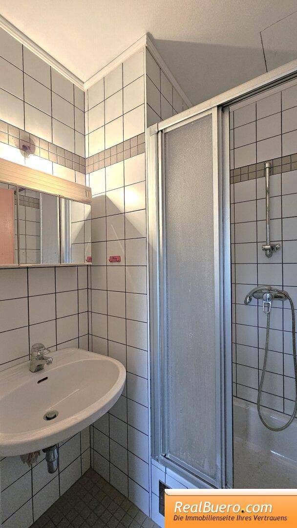 Badezimmer mit Dusche und Handwaschbecken