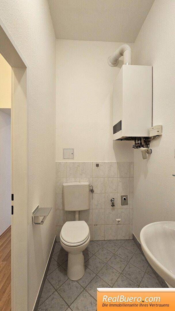 Badezimmer mit Dusche, Handwaschbecken, Waschmaschinenaschluss und Toilette