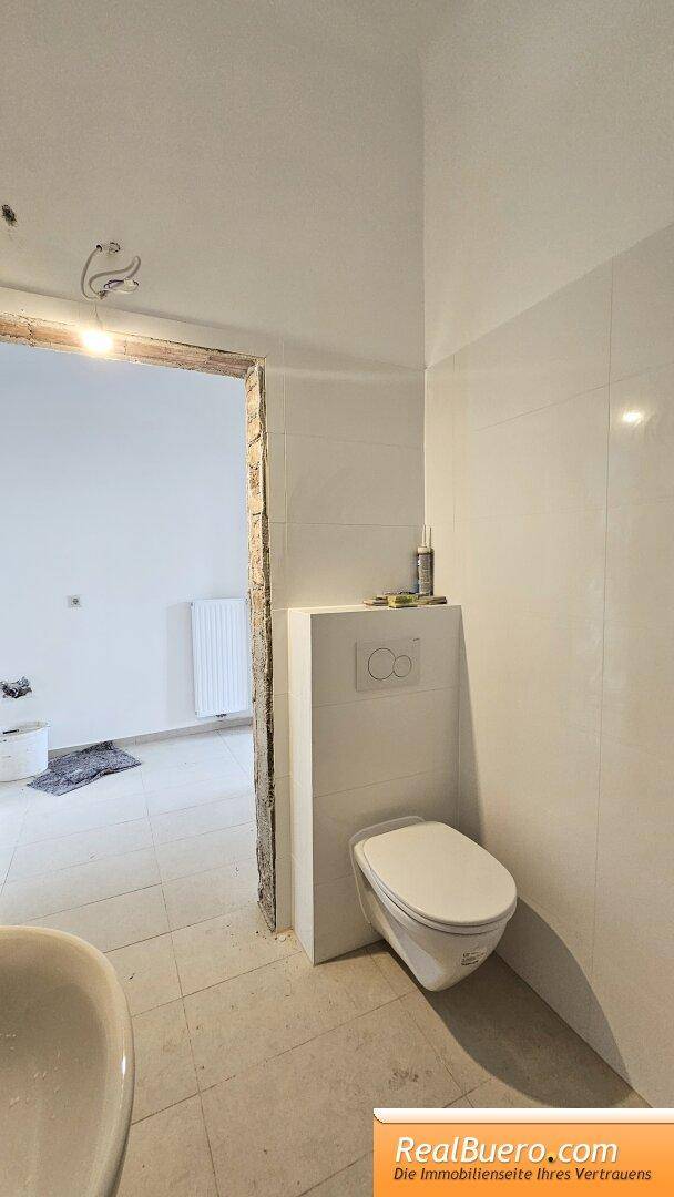 Badezimmer mit Dusche Handwaschbecken Toilette und Waschmaschinenanschluss