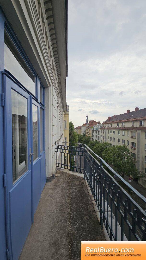 Schmaler Balkon mit Metallgeländer und Blick auf die umliegenden Gebäude der Stadt.