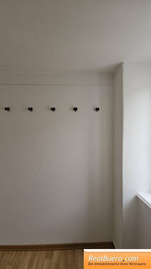 Heller Raum mit Holzboden und einer Reihe von Wandhaken.