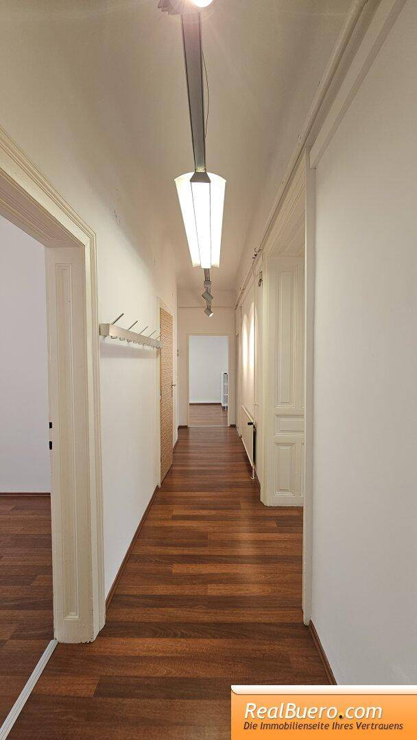 Langer Flur mit Holzfußboden, Garderobe und Türen zu angrenzenden Räumen.