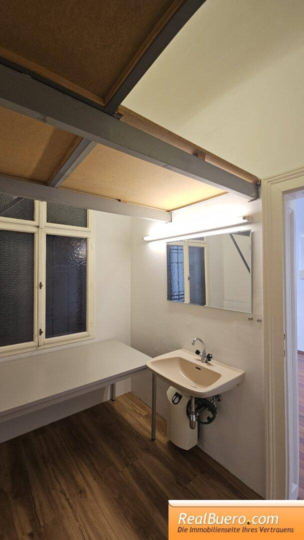 Badezimmer mit Waschbecken, Fenster und einer Ablage unter der Decke.