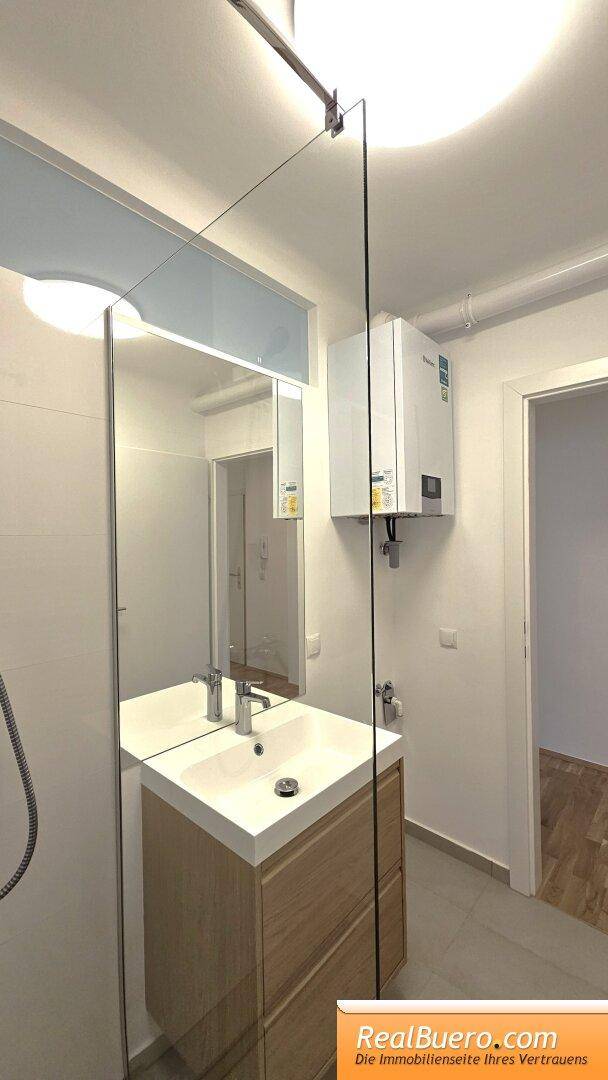 Badezimmer mit Dusche, Handwaschbecken und Waschmaschinenaschluss
