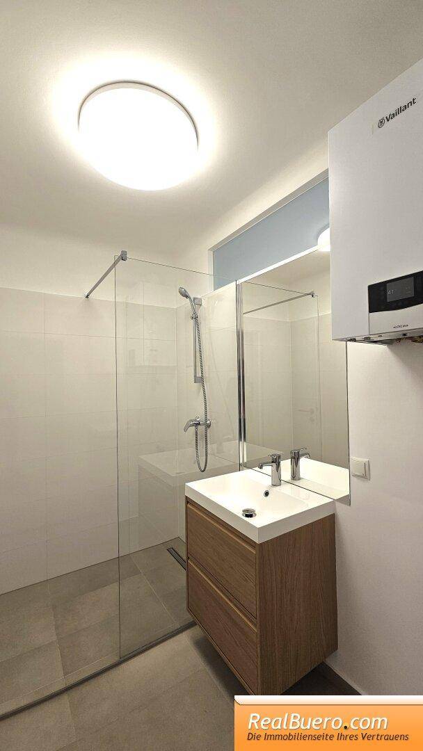 Badezimmer mit Dusche, Handwaschbecken und Waschmaschinenaschluss