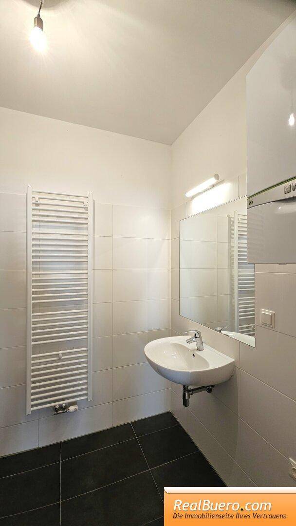Badezimmer mit Wanne, Handwaschbecken, Waschmaschinenanschluss, Handtuchtrockner