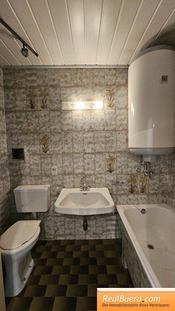 Badezimmer mit Wanne, Toilette, Handwaschbecken, Waschmaschinenanschluss