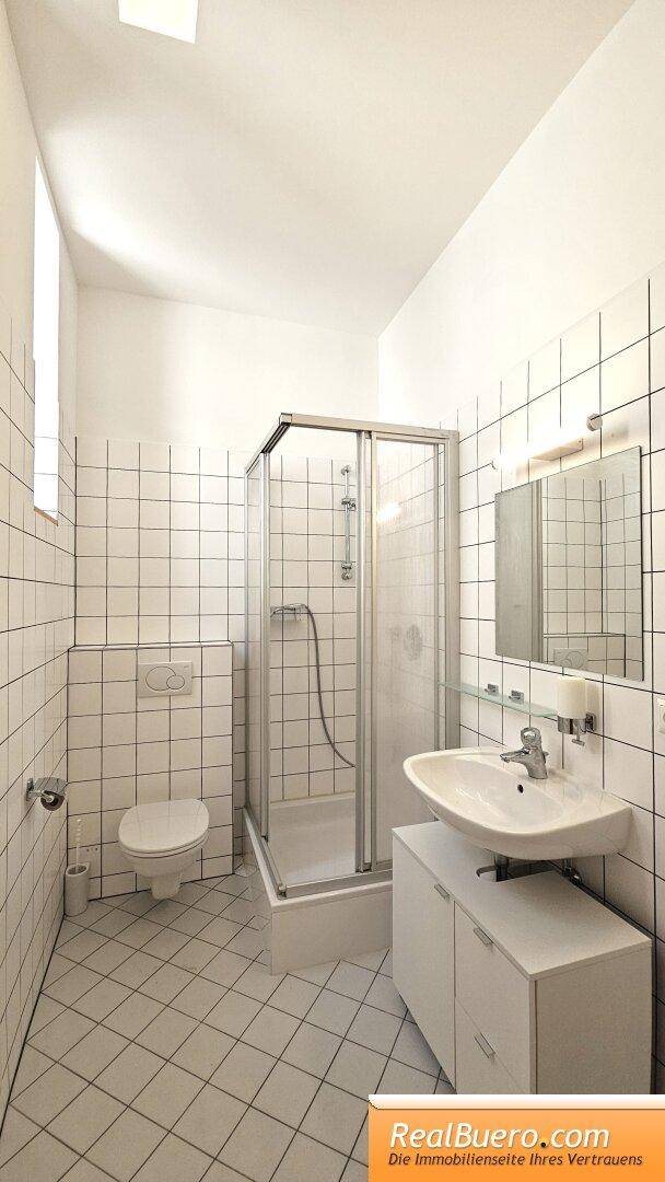 Badezimmer mit Dusche, Handwaschbecken, Handtuchtrockner und Toilette