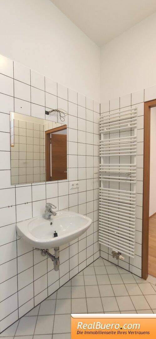 Badezimmer mit Dusche, Handwaschbecken, Handtuchtrockner und Toilette
