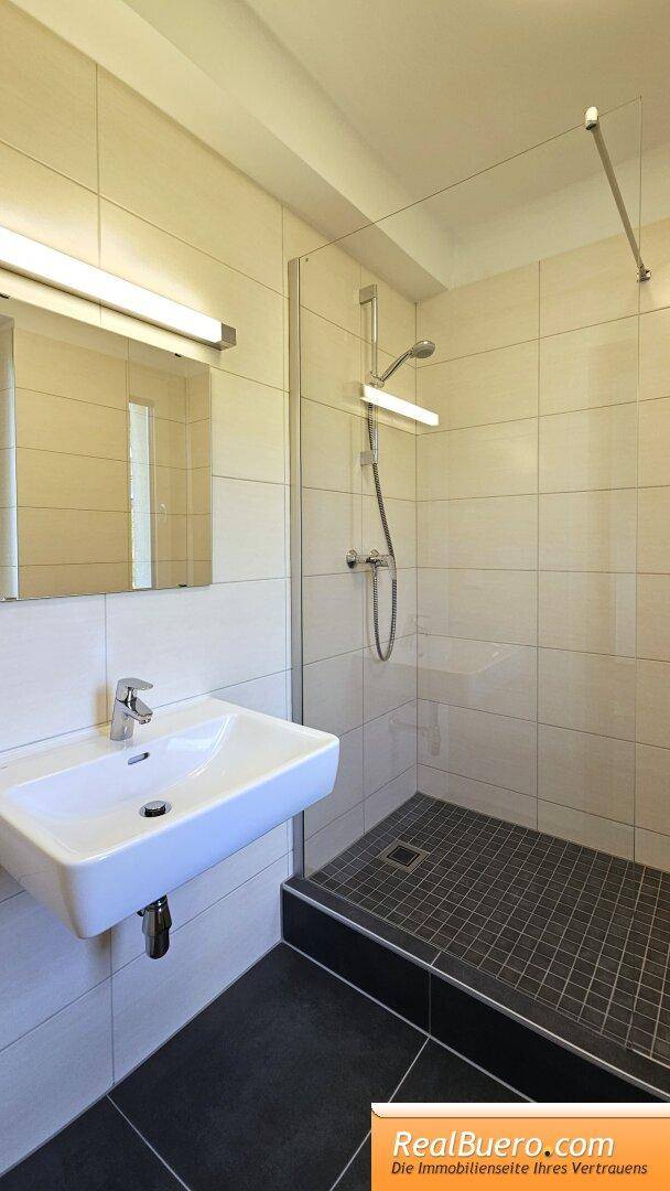 Badezimmer mit Dusche und Handwaschbecken