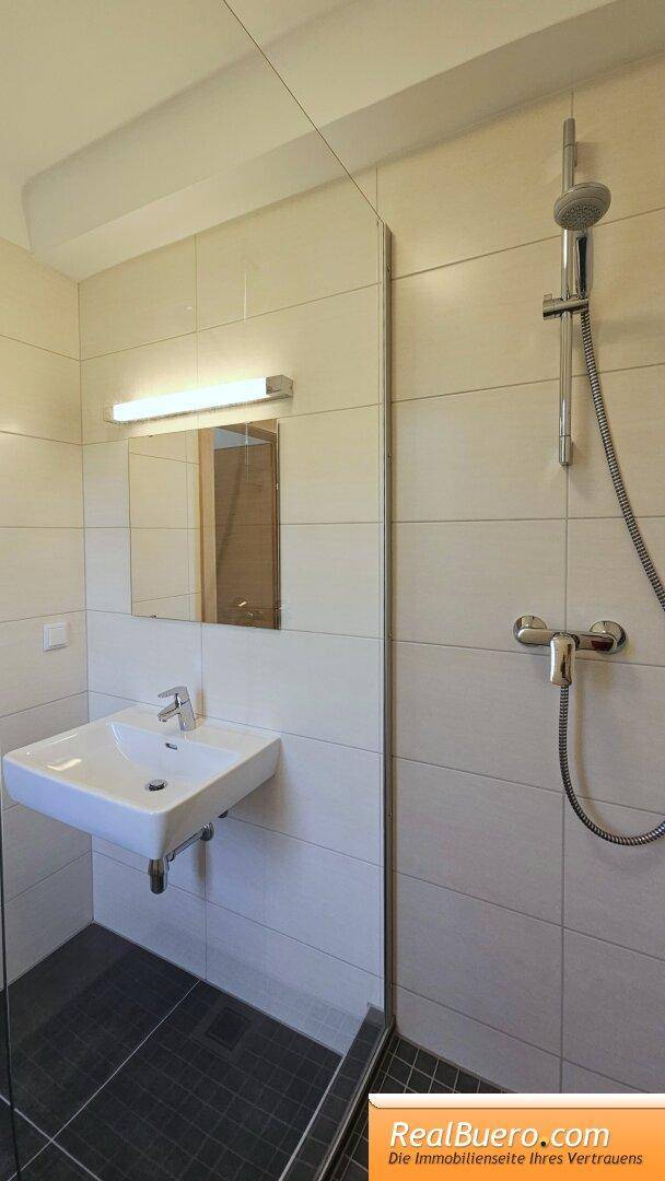 Badezimmer mit Dusche und Handwaschbecken