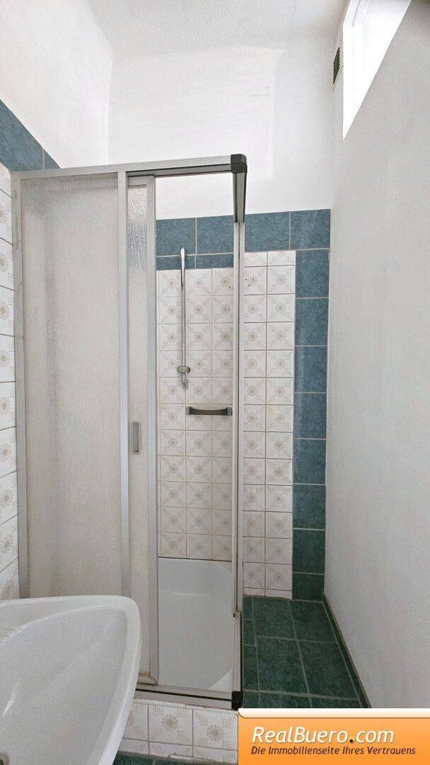 Kleines Bad mit Dusche, Handwaschbecken und Waschmaschinenanschluss