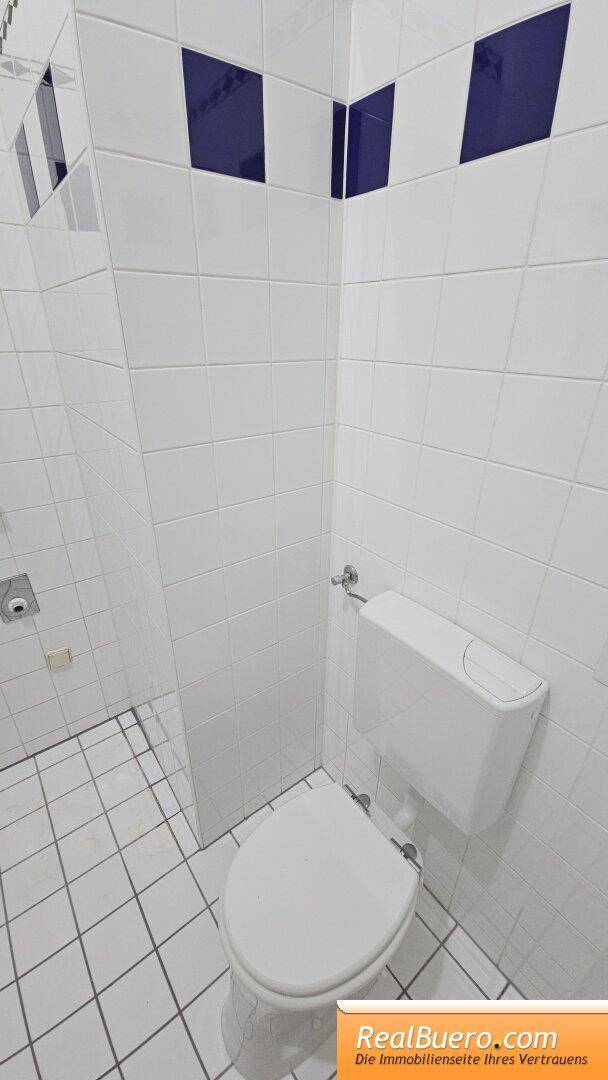 Badezimmer mit Dusche, Handwaschbecken, Toilette und Waschmaschinenaschluss