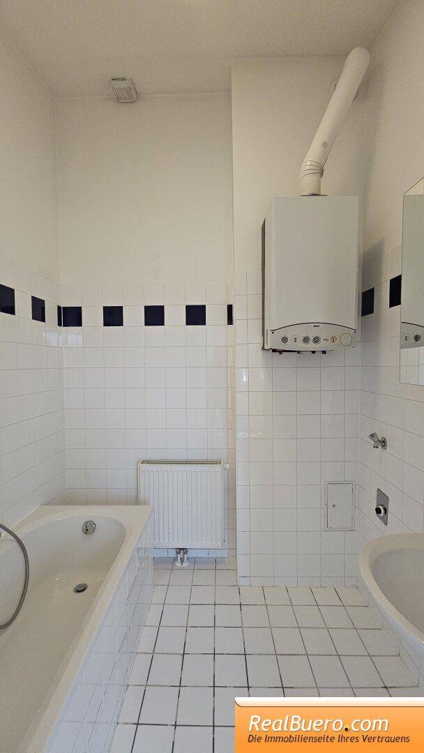 Badezimmer mit Wanne, Handwaschbecken und Waschmaschinenanschluss