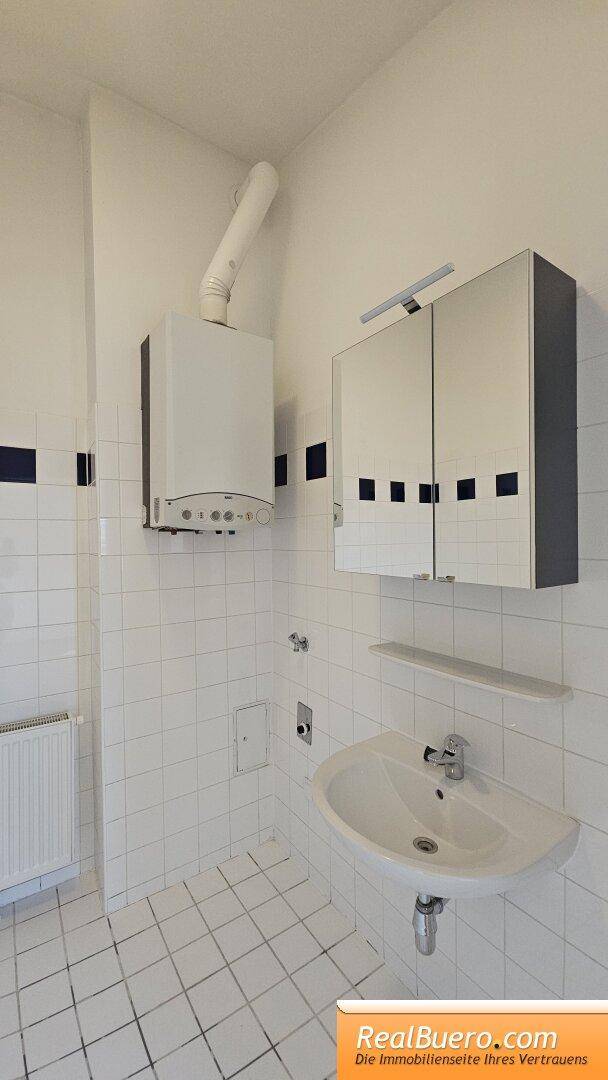 Badezimmer mit Wanne, Handwaschbecken und Waschmaschinenanschluss