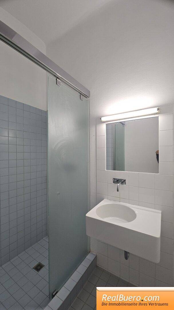 Badezimmer mit Dusche, Handwaschbecken und Waschmaschinenaschluss