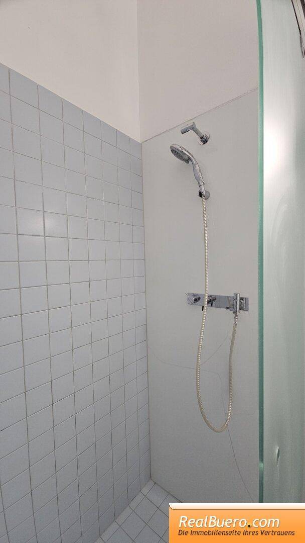 Badezimmer mit Dusche, Handwaschbecken und Waschmaschinenaschluss