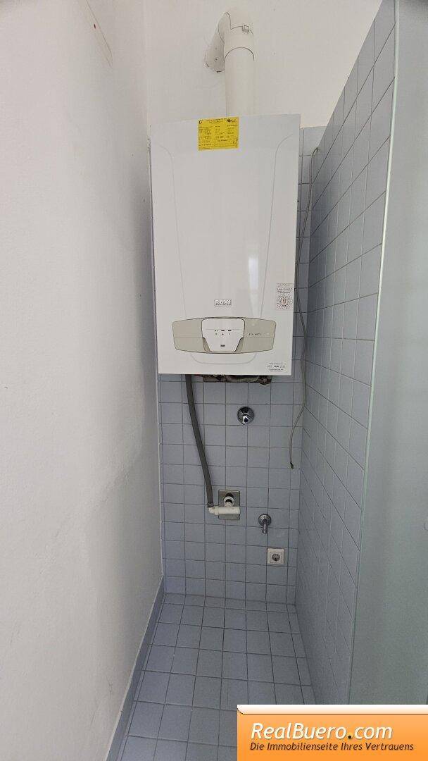 Badezimmer mit Dusche, Handwaschbecken und Waschmaschinenaschluss