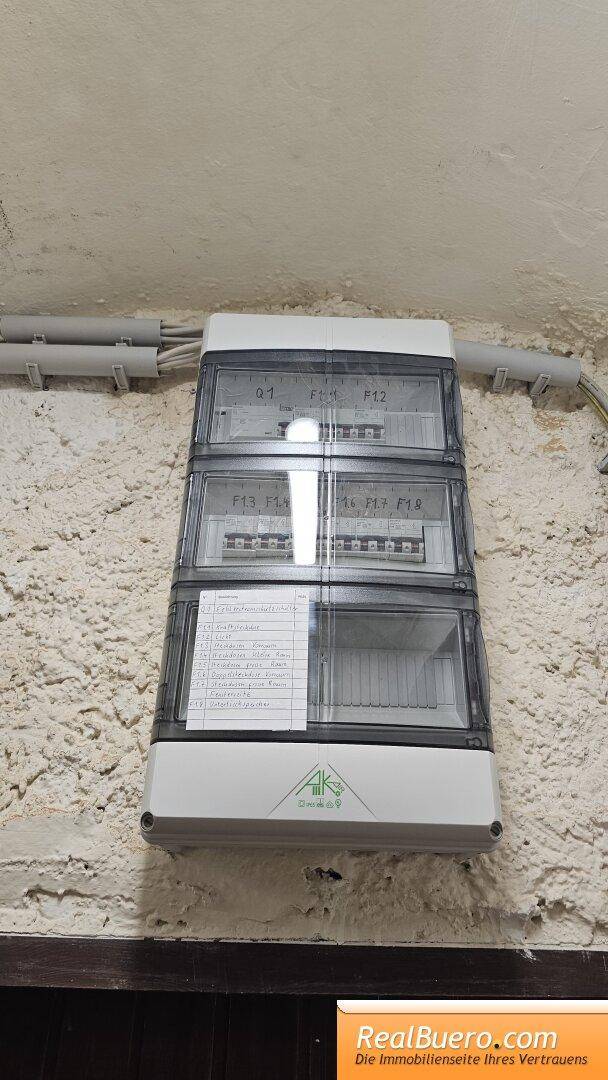Nahaufnahme eines modernen Sicherungskastens an einer rauen Wand, der die elektrische Versorgung regelt.