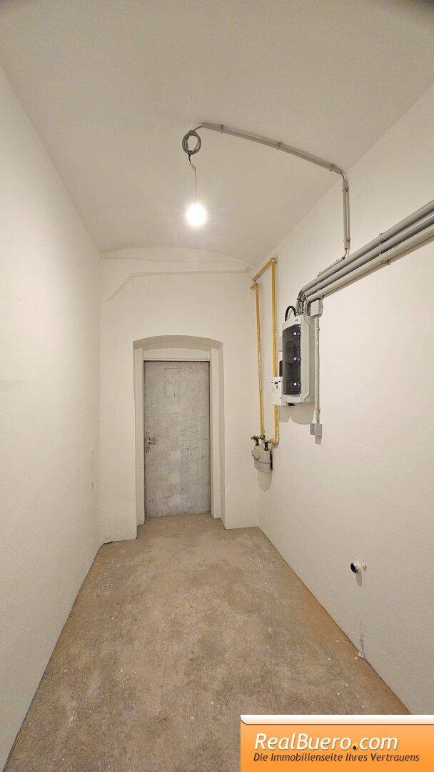 Schmaler Raum mit sichtbaren Gasleitungen und einem Sicherungskasten an der Wand.