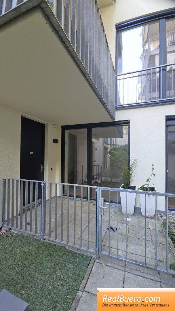Erdgeschoss-Terrasse mit Metallzaun und Pflanzenkübeln, bietet direkten Zugang zum Außenbereich.