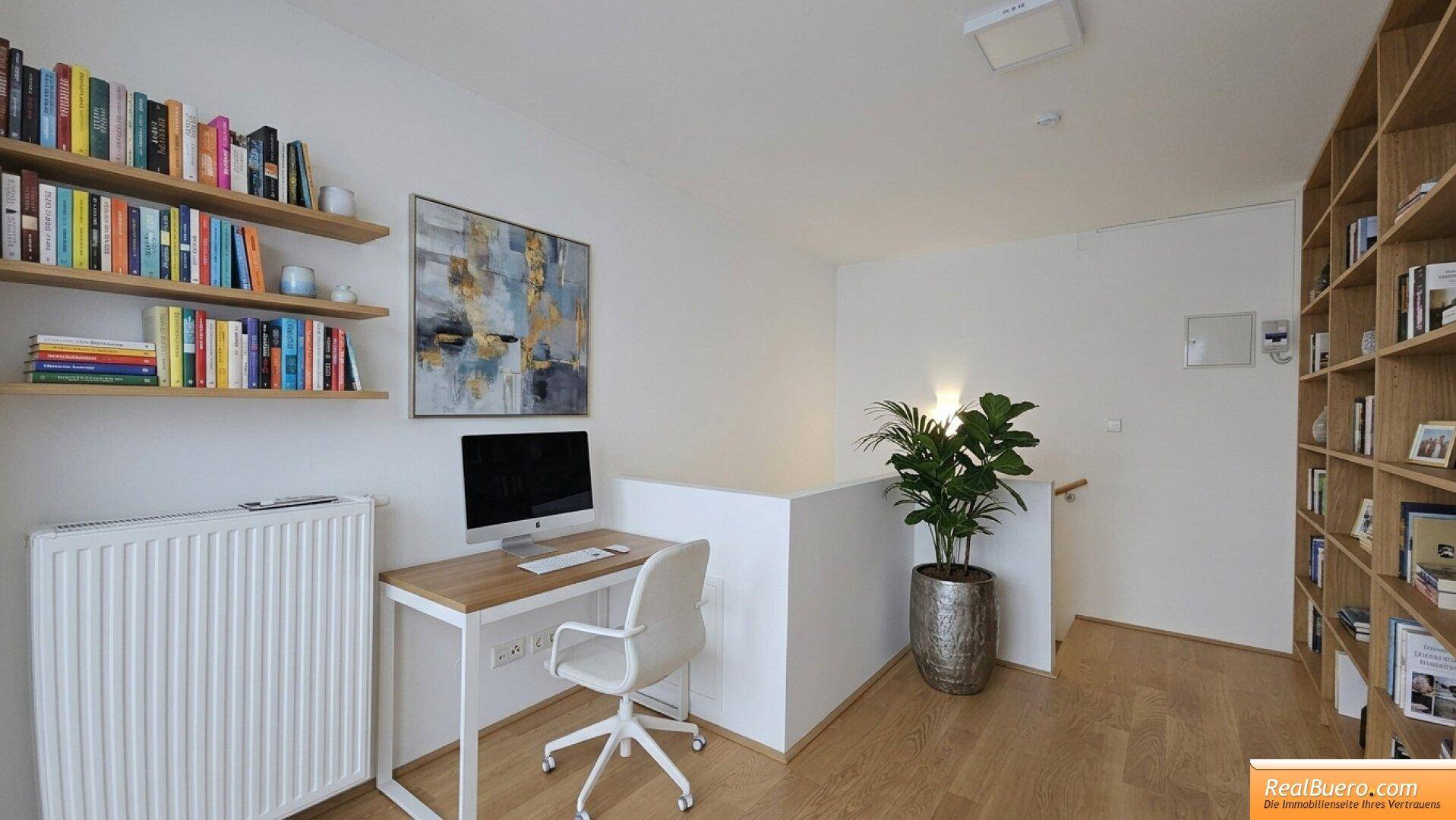 Heller Arbeitsbereich mit Schreibtisch, Bücherregalen und Blick auf das Treppenhaus.
