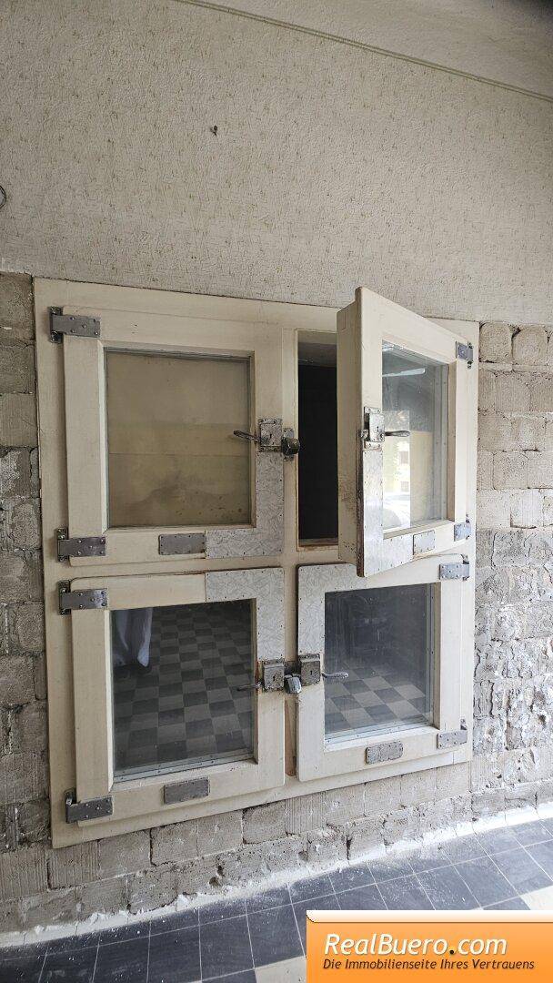 Detailansicht alter Fenster in einem renovierungsbedürftigen Raum mit kariertem Fliesenboden.
