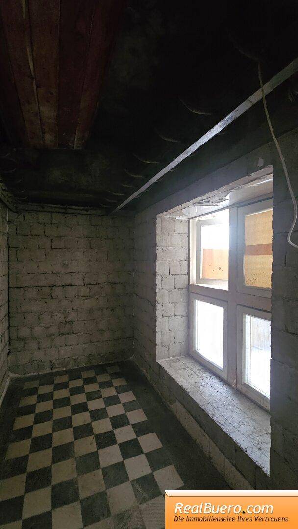 Kellerraum mit kariertem Fliesenboden und einem kleinen Fenster, das Tageslicht hereinlässt.