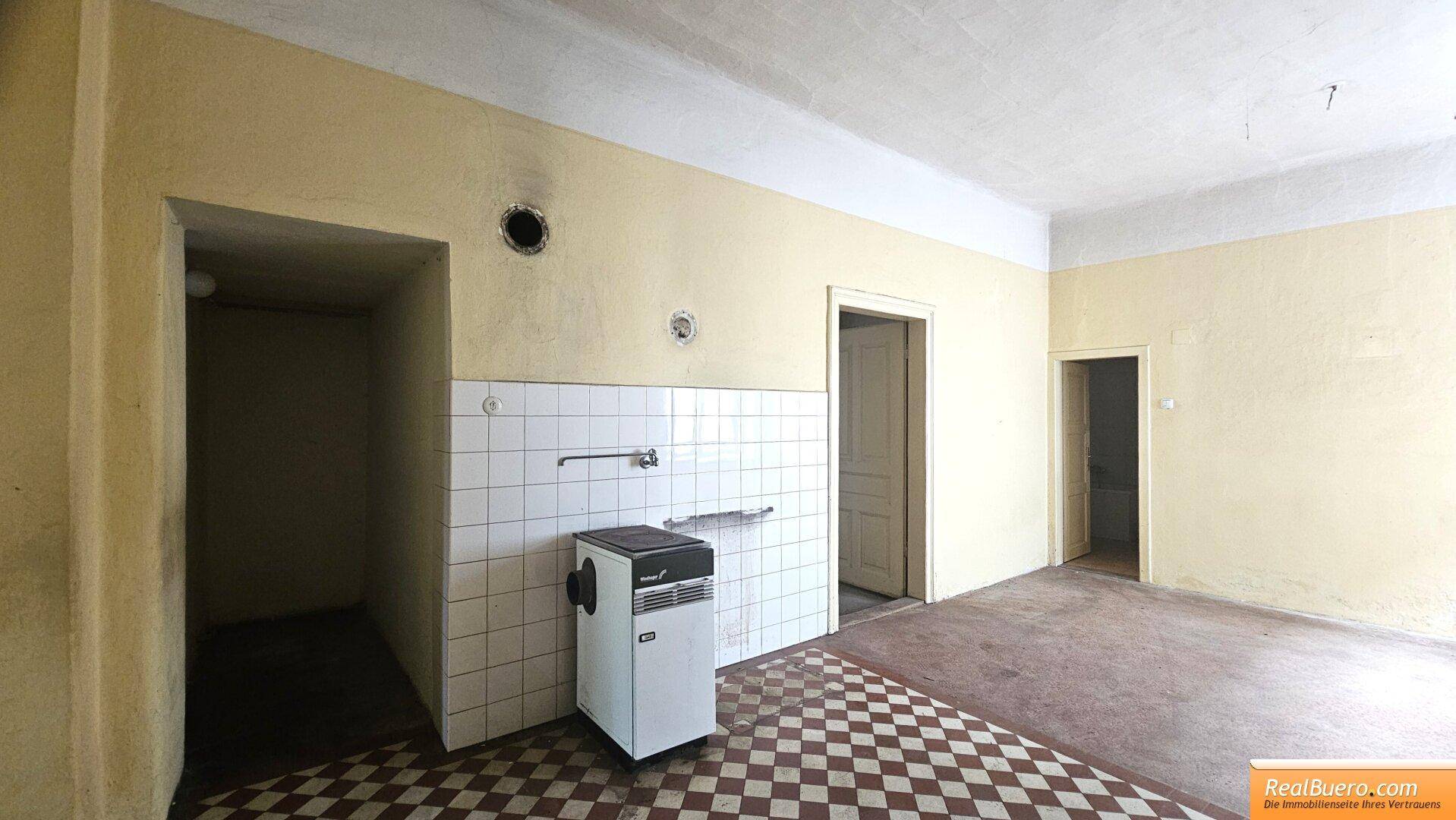 Küche in renovierungsbedürftigem Zustand mit kariertem Fliesenboden und Wandfliesen.