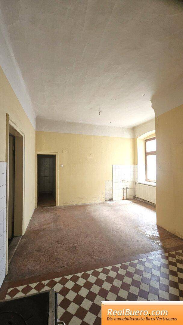 Geräumige Küche mit kariertem Fliesenboden und gelben Wänden, bereit für eine Modernisierung.