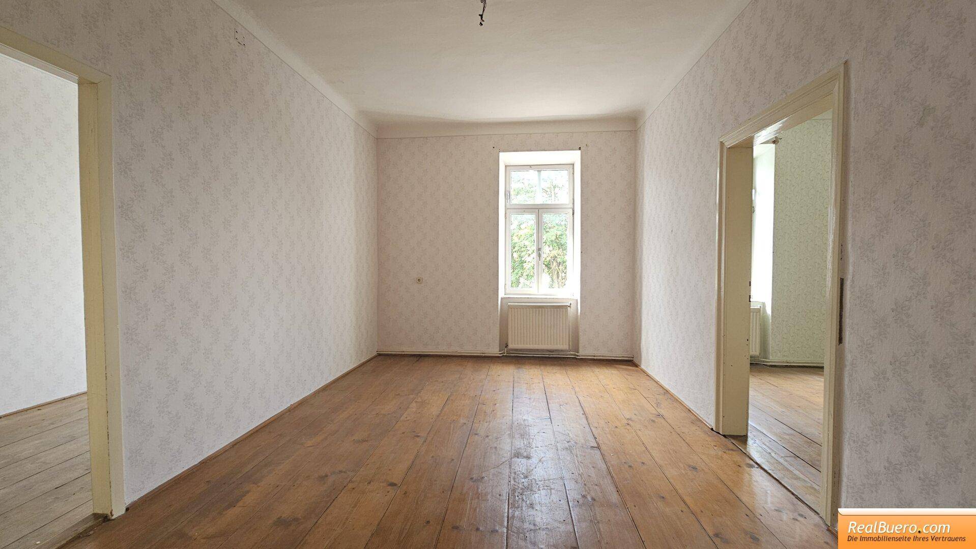 Heller Raum mit Holzdielenboden und einem Fenster, bietet Potenzial für individuelle Gestaltung.