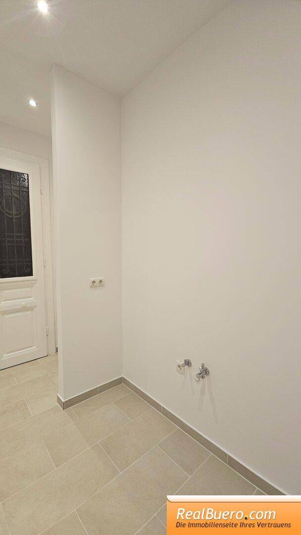 Leerer Raum mit Anschlüssen an der Wand, möglicherweise für eine Küche oder Waschküche vorgesehen.