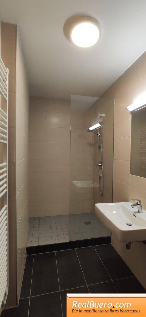 Modernes Badezimmer mit Duschkabine, Waschbecken und beheiztem Handtuchhalter.