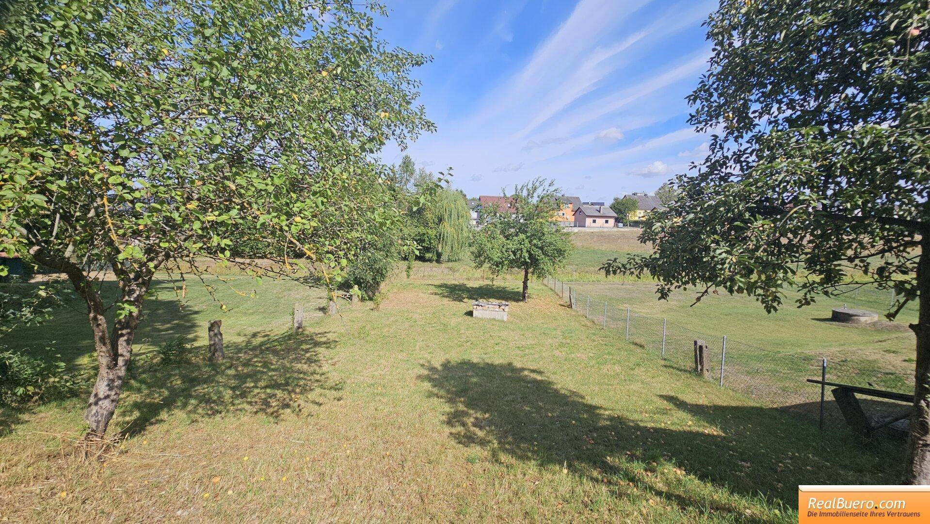 Grüner Gartenbereich mit mehreren Obstbäumen und weitem Blick auf die ländliche Umgebung.