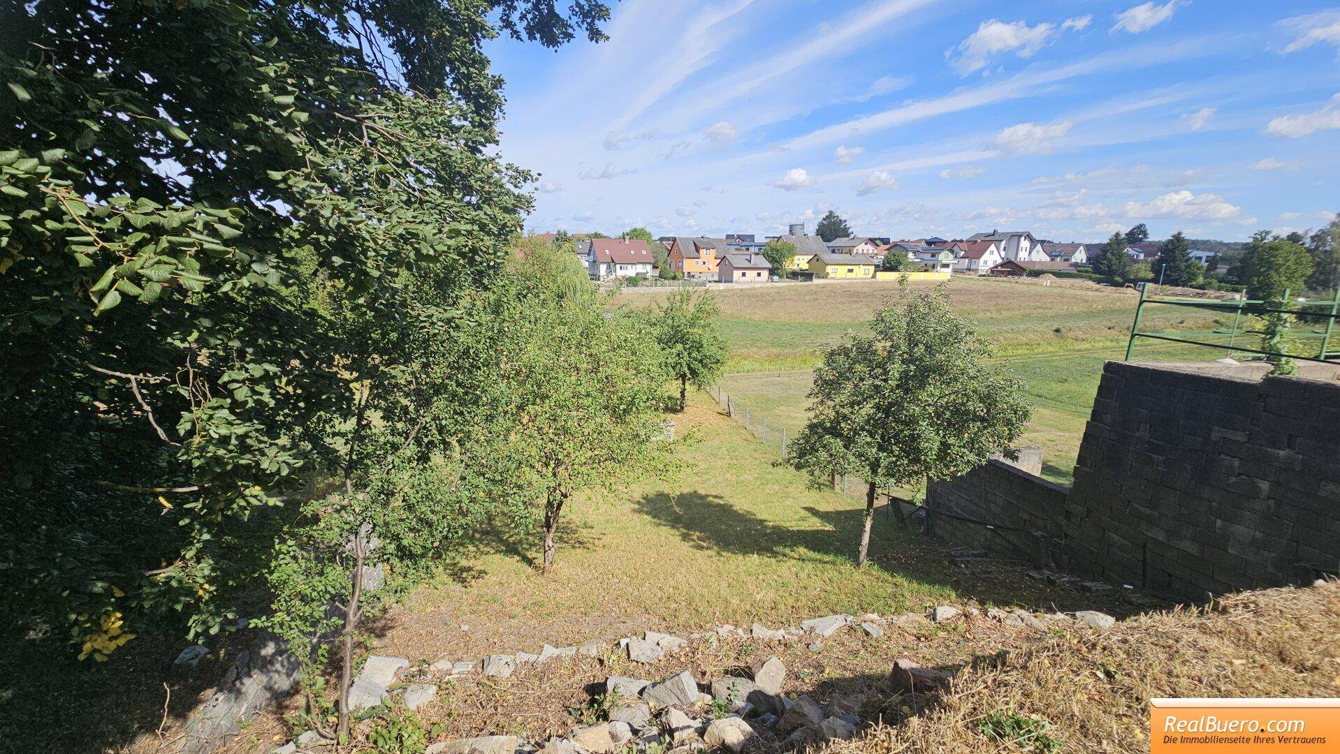 Weitläufiger Garten mit Obstbäumen und einer alten Steinmauer, bietet einen schönen Blick.