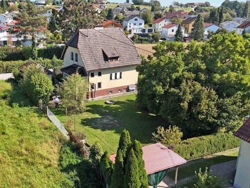 Rückansicht des Hauses mit weitläufigem Garten und einem kleinen überdachten Sitzbereich.