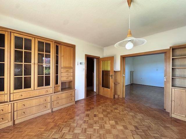Geräumiges Wohnzimmer mit Fischgrätparkettboden und massiven Holzschränken im klassischen Stil.